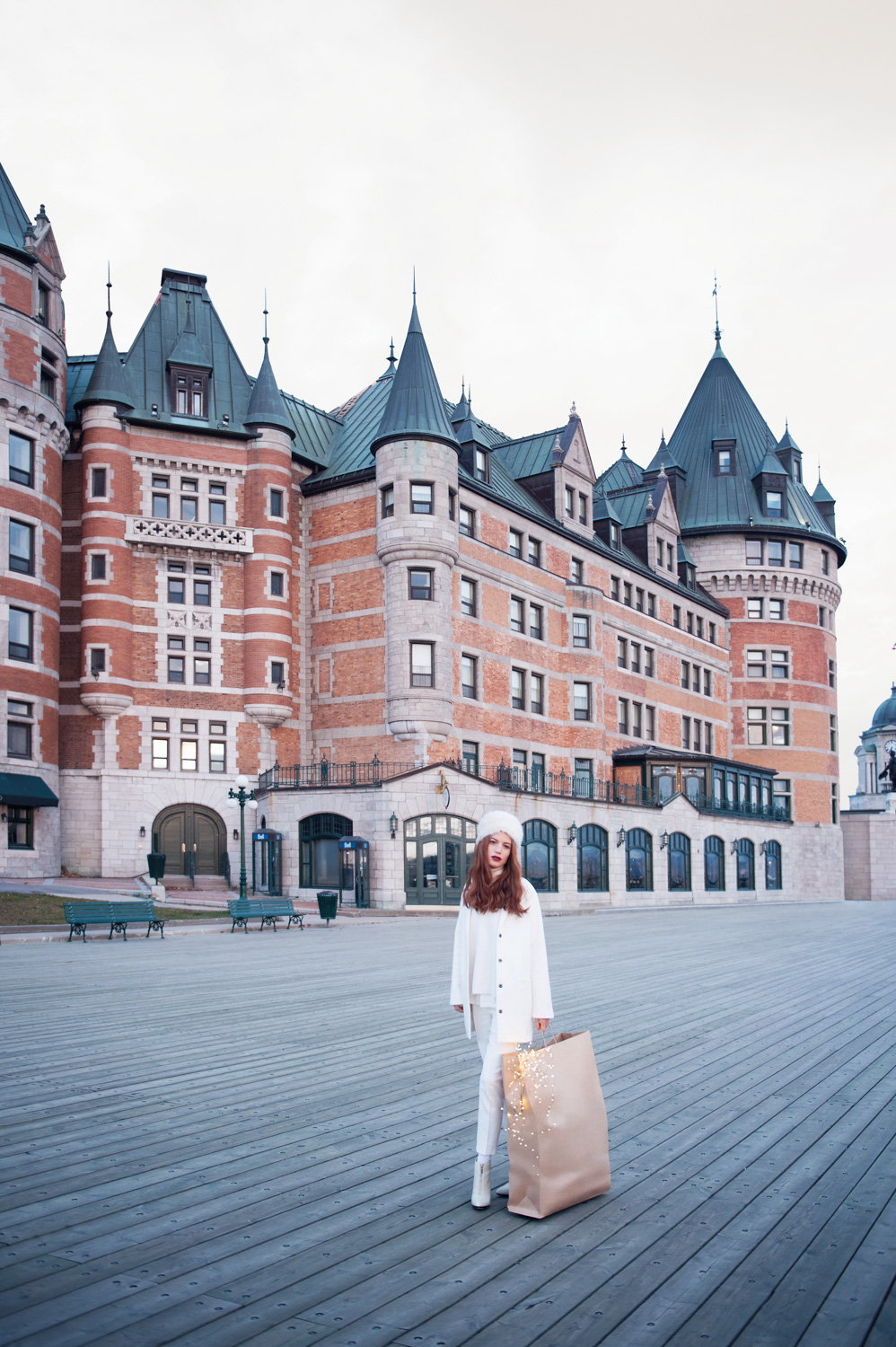 A woman in all white holding a bag outside of castle-looking building