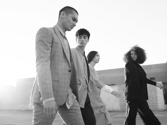 Two men and two women in business attire walking down a street