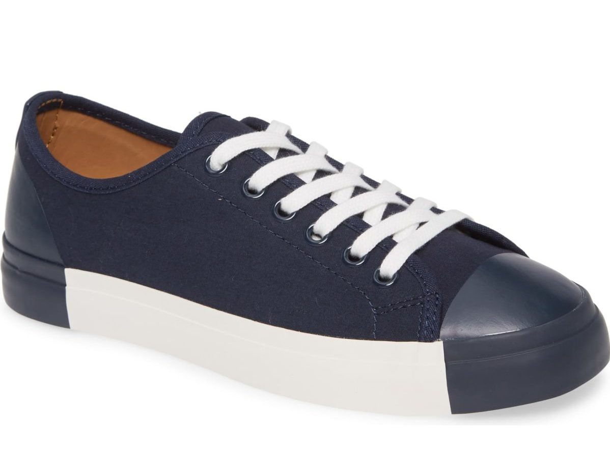 A navy blue sneaker with white shoe laces and a cream color sole