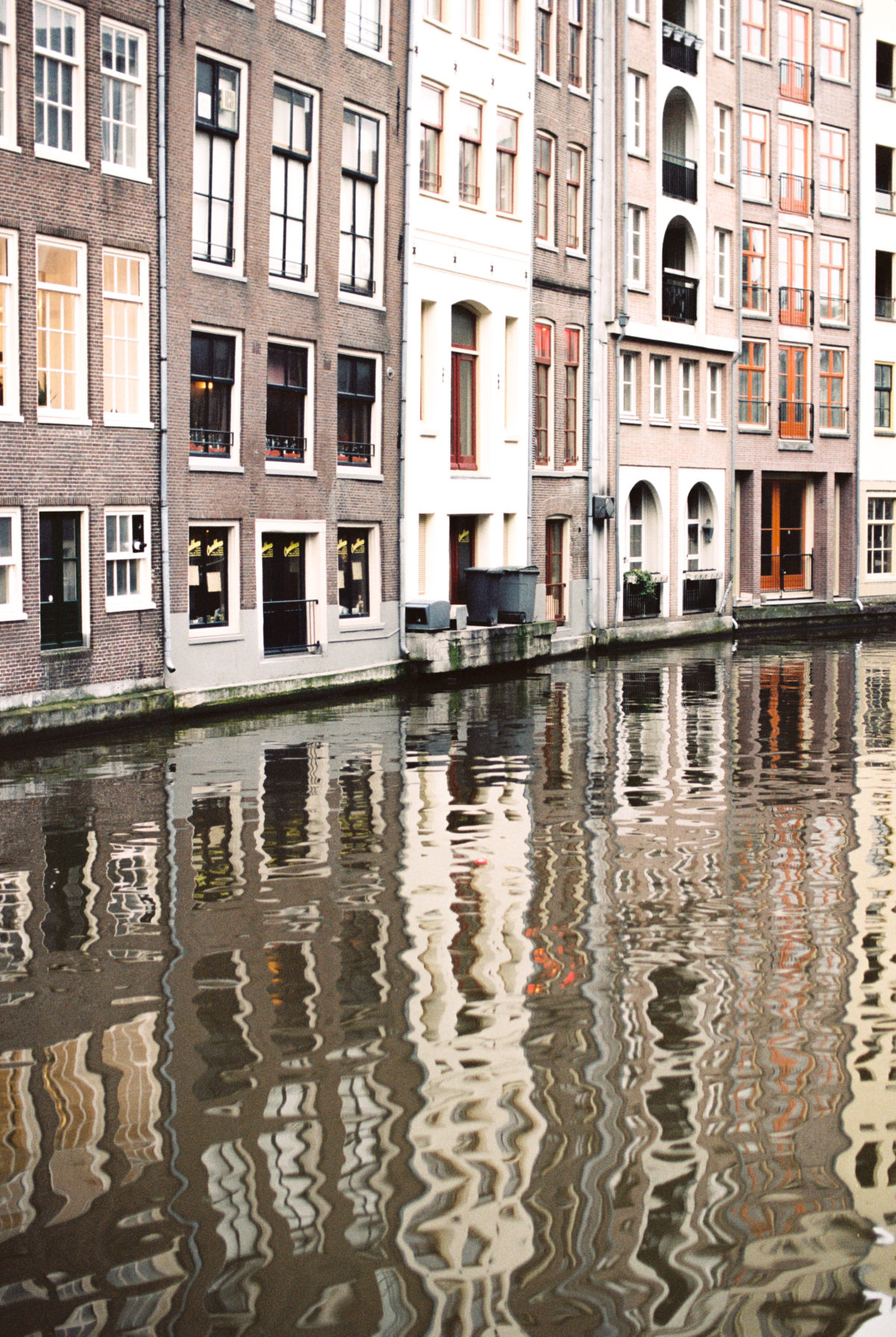 A river in Amsterdam flowing behind a row of buildings
