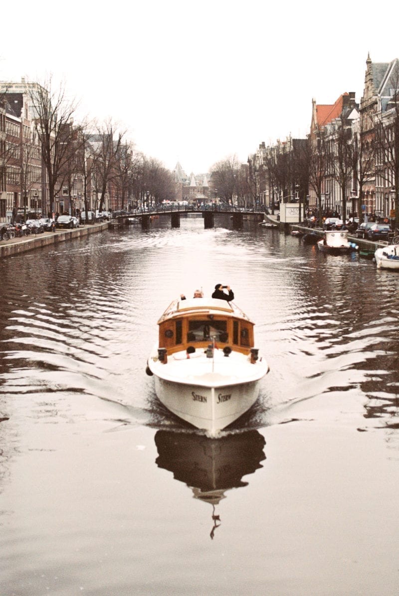 A small boat flowing down a river in Amsterdam
