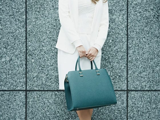 A woman holding a purse in a business power suit