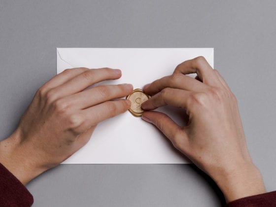 hands touching the seal on an envelope