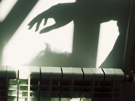An image of the shadow of a person learning over a wall heater