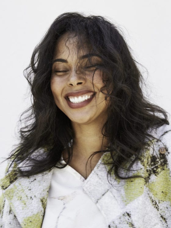 A woman smiling as her curly hair blows in the wind