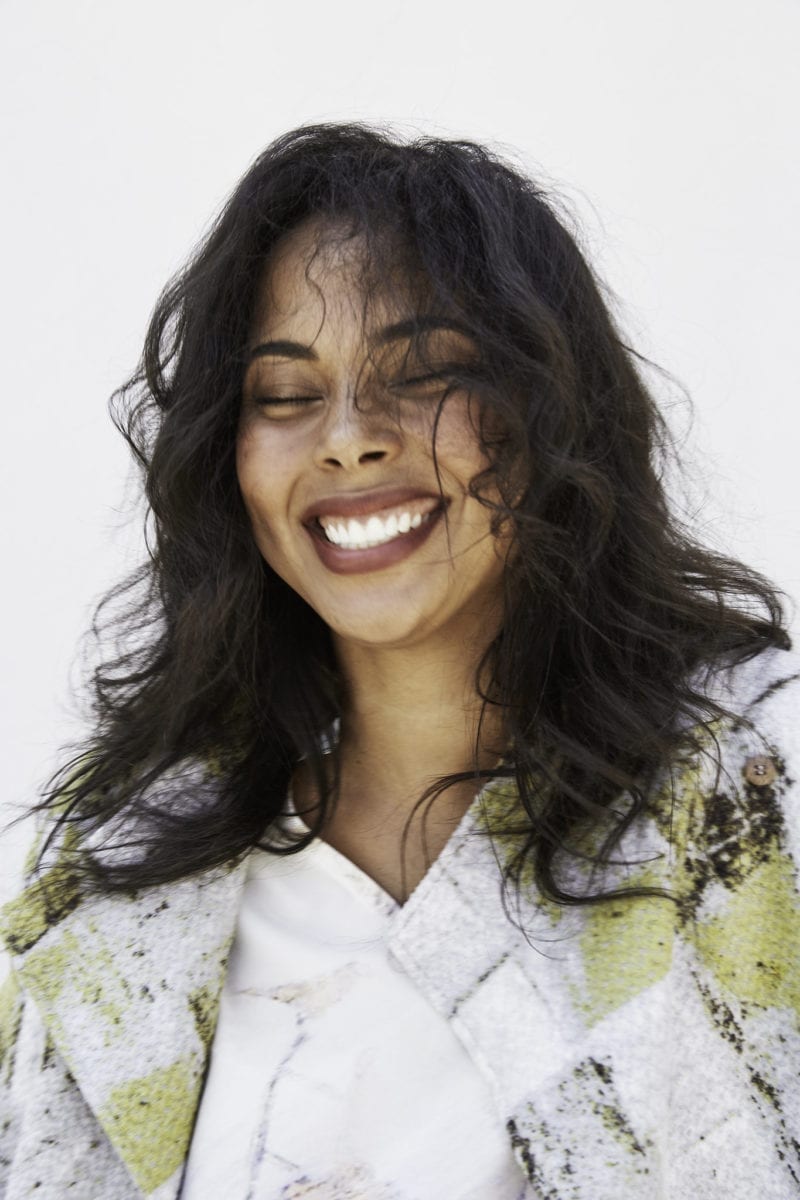 A woman smiling as her curly hair blows in the wind