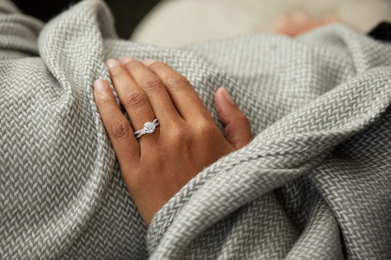 A woman's ring hand under a blanket