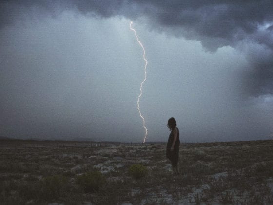 A woman standing in a field with lightning