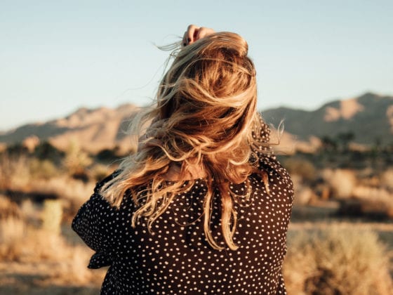 The back of a woman as she stands in front of beautiful mountains in the distance