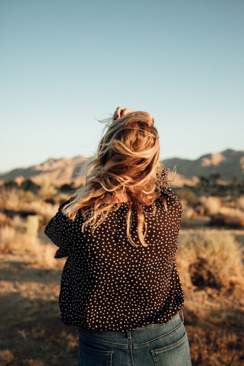 The back of a woman as she stands in front of beautiful mountains in the distance
