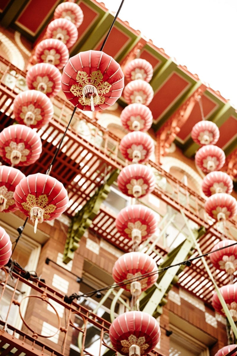 A close up image of paper lanterns hanging from an outside balcony