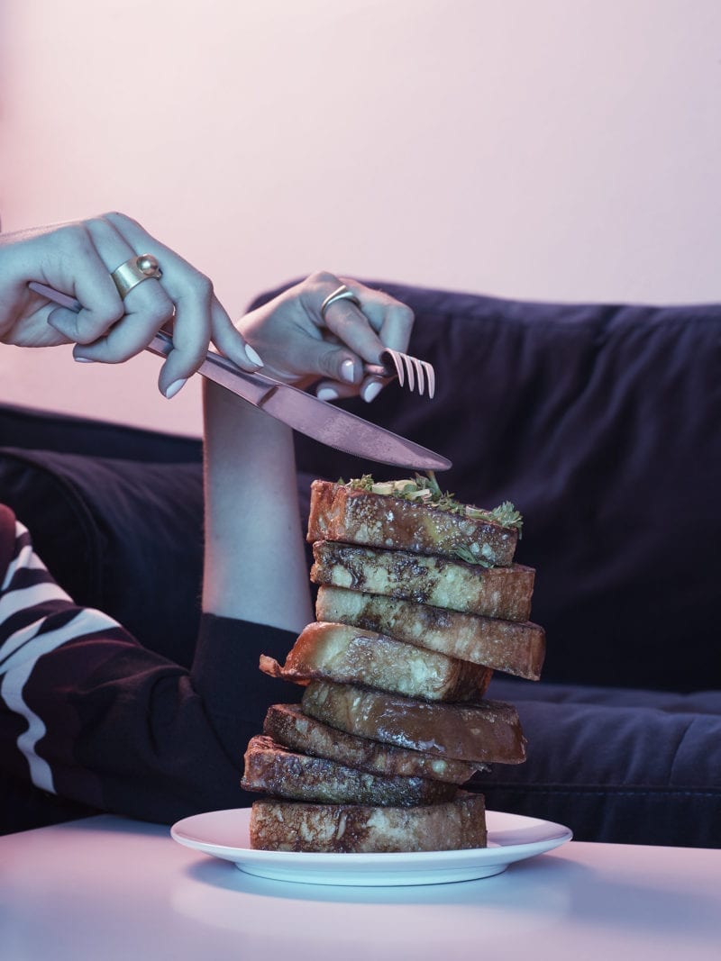 A woman's hands as she's cutting French toast on a plate