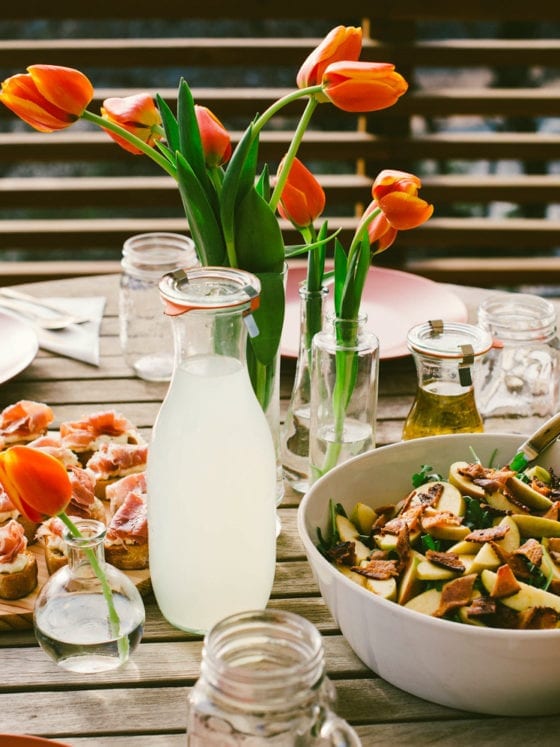 A table of food with a vase of tulips at the center