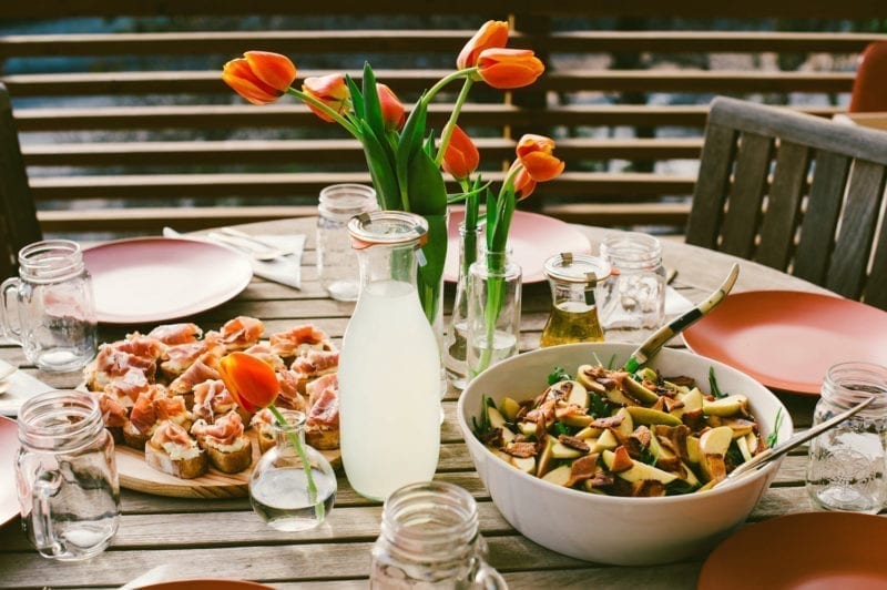 A table of food with a vase of tulips at the center