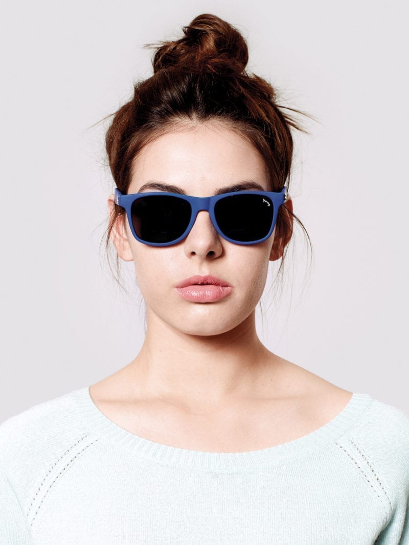 A woman with sunglasses and a top bun