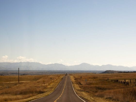 A picture of a road through a plains with mountains in the background