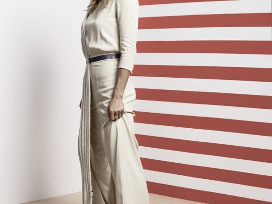 A woman standing in from of a wall of red stripes