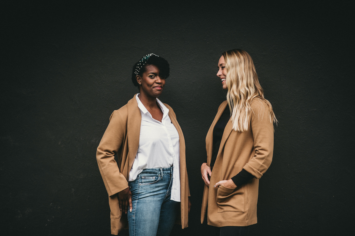Two women smiling in trench jackets