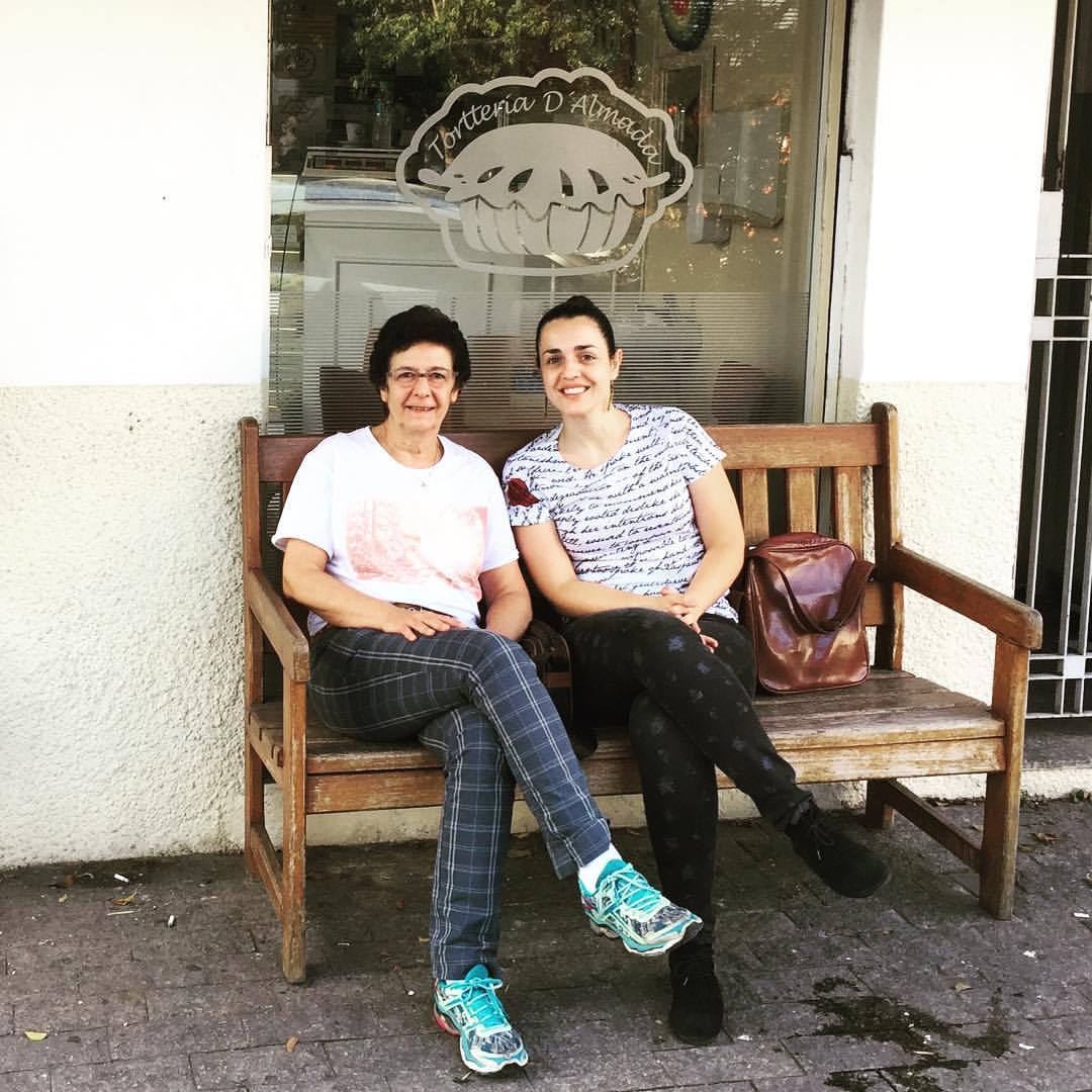 Two women seated on a bench outside a bakery