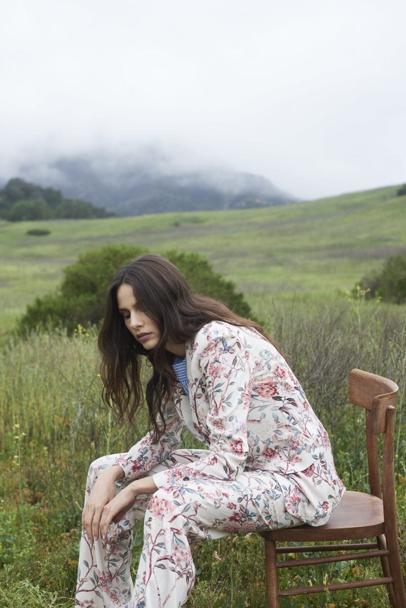 A woman sitting on a chair outside in a hilly area that is overcast