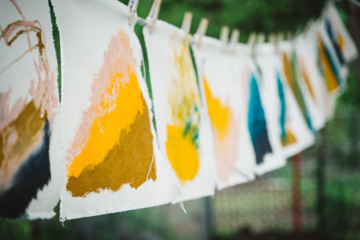A hanging line of paintings drying outside