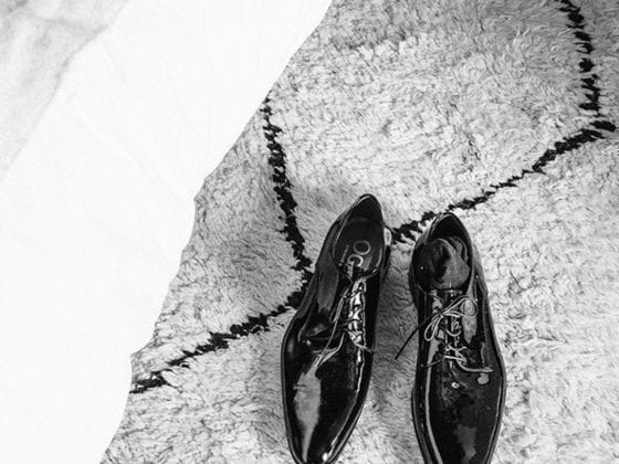 A black and white photo of a man's dress shoes on a rug