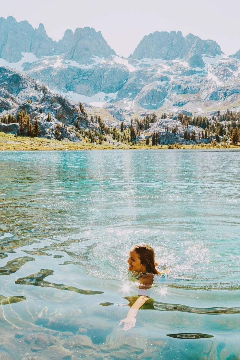 A woman swimming in a river with mountains in the distance