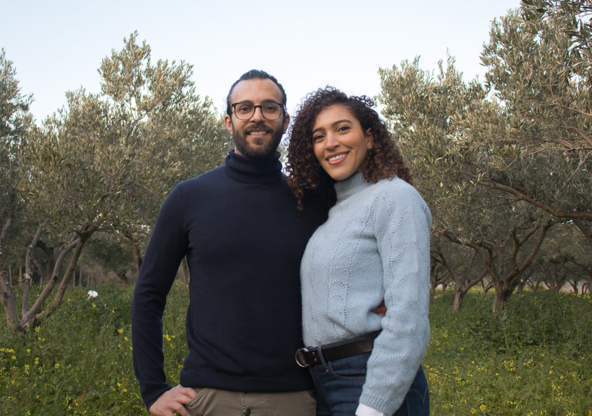 A couple standing in front of olive trees