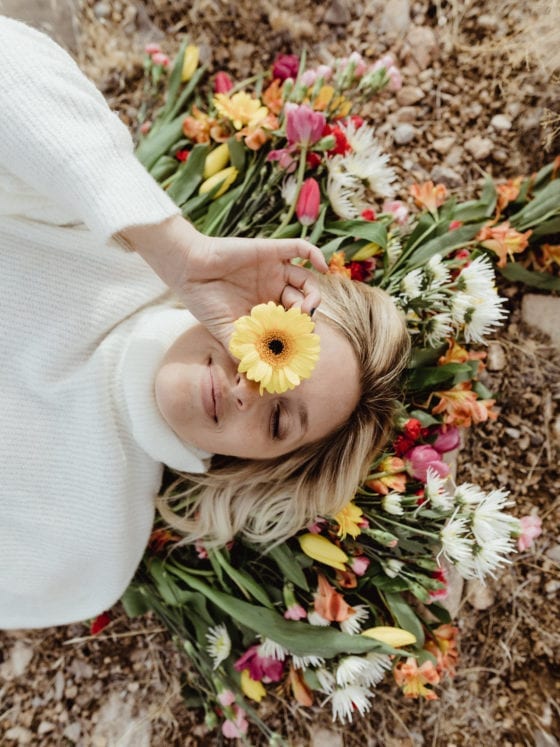 A woman lying atop flowers on the ground