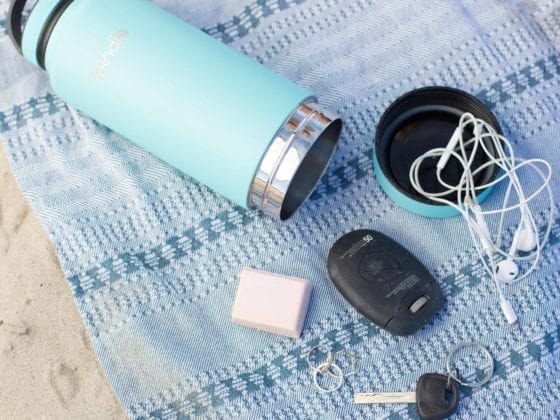 A water bottle, keys and headphones lying on a blanket