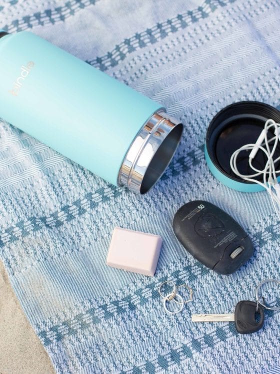 A water bottle, keys and headphones lying on a blanket