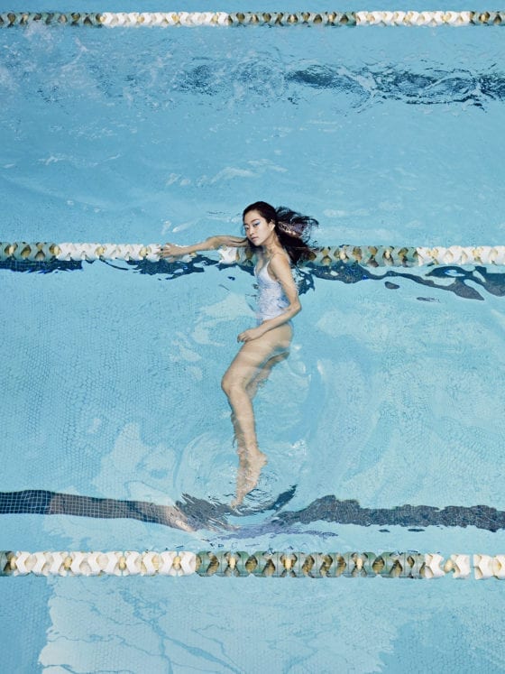 A woman lying on a lane divider in an Olympic pool