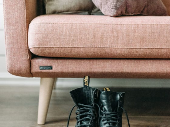 A pair of black boots by a pink sofa