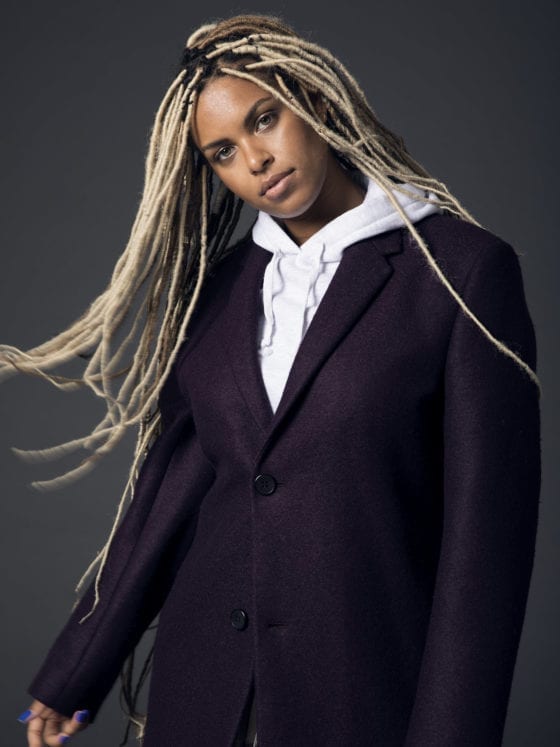 A black woman with long blonde braids blowing in the wind