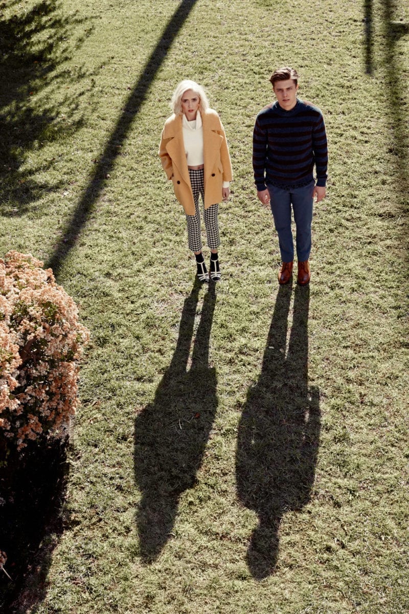 A man and woman standing in the sun on a lawn with their shadows in front of them