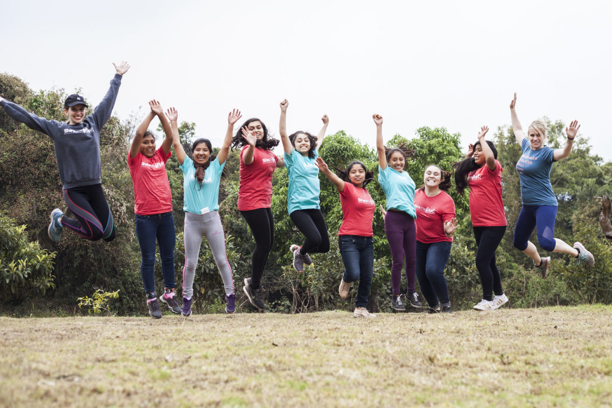 A group of girls jumping and smiling in hiking clothes