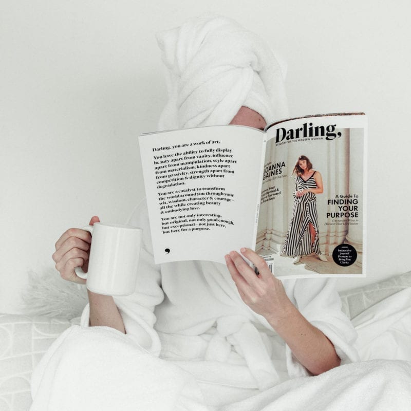 A woman reading a magazine in a towel and robe as she sips coffee