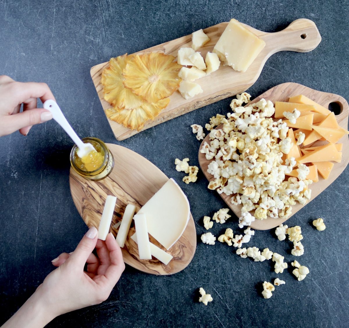 A cutting board with cheese and popcorn