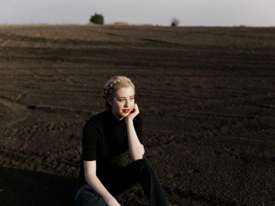 A woman wearing all black sitting in a field