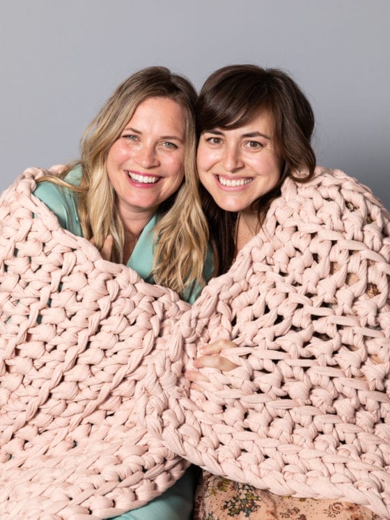 Two women wrapped under a blanket