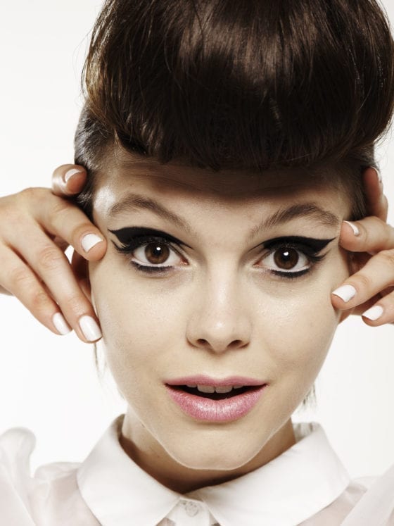A woman with her hands on her face near her eyes with a cat eye's winged mascara look