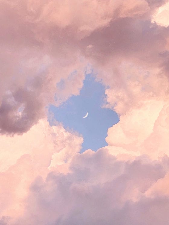 A photo of pink clouds with a moon in the middle of it