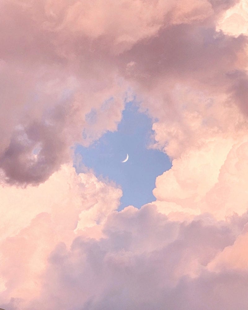 A photo of pink clouds with a moon in the middle of it