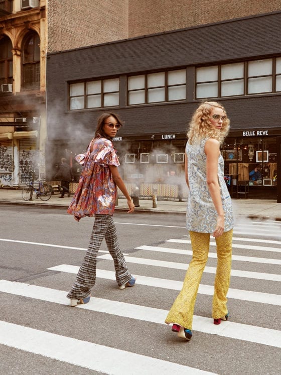 Three posh women crossing a New York Street as they look over their shoulders and back at the camera