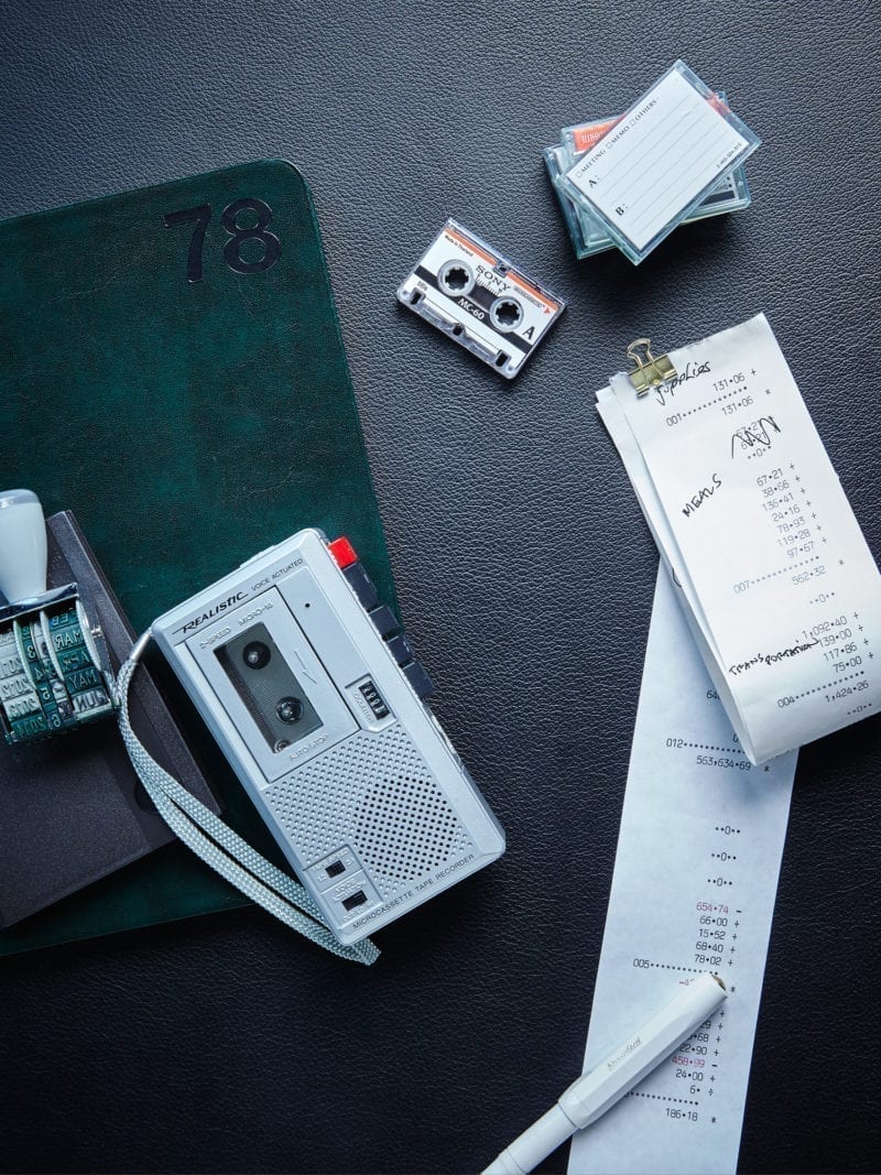 A recorder, receipts, and audio cassettes on a desk
