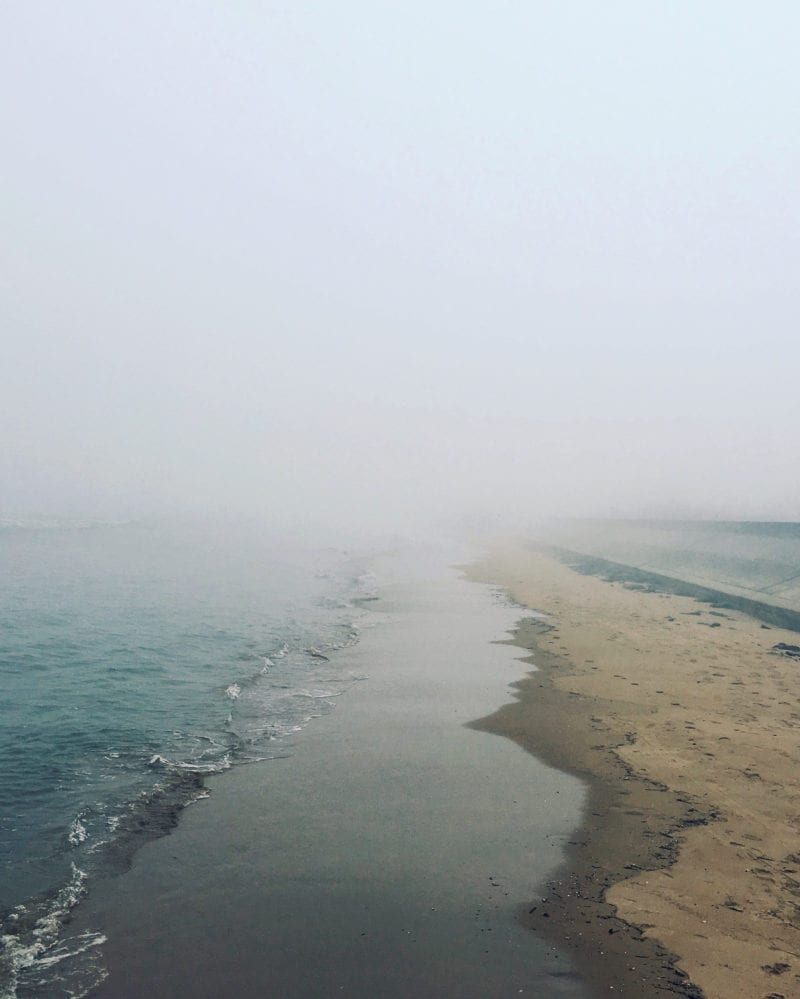 A foggy day at the beach as the waves meet the shore