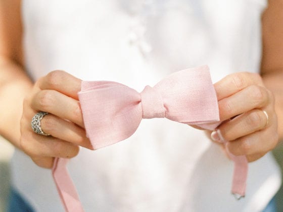 A woman holding a pink headband with a bow atop it