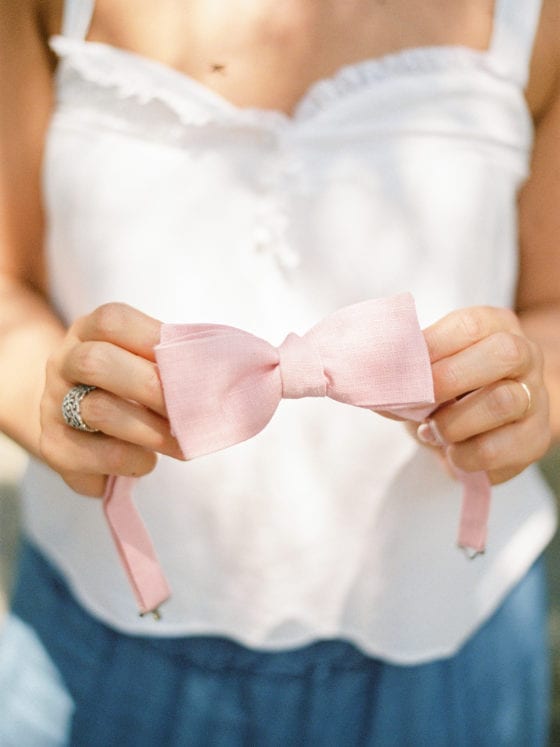 A woman holding a pink headband with a bow atop it