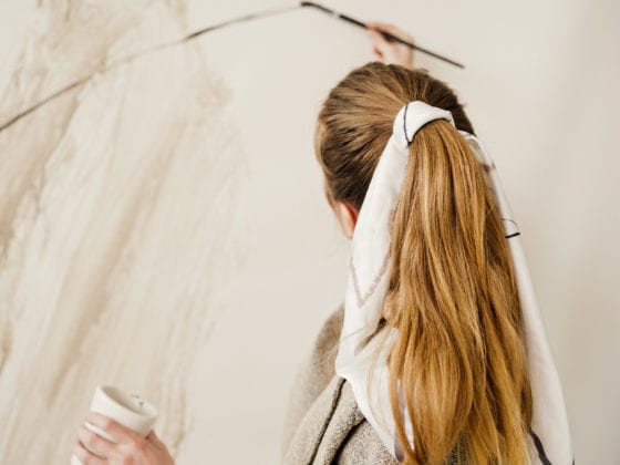 A woman painting as her back faces the camera