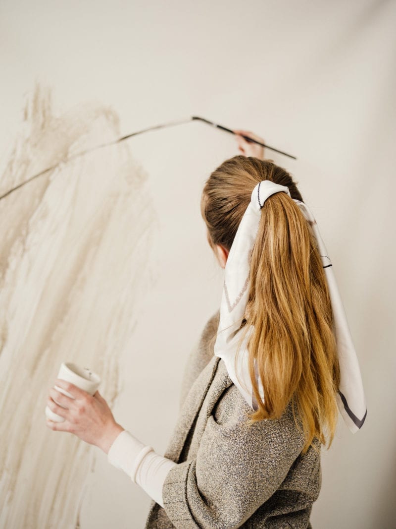 A woman painting as her back faces the camera